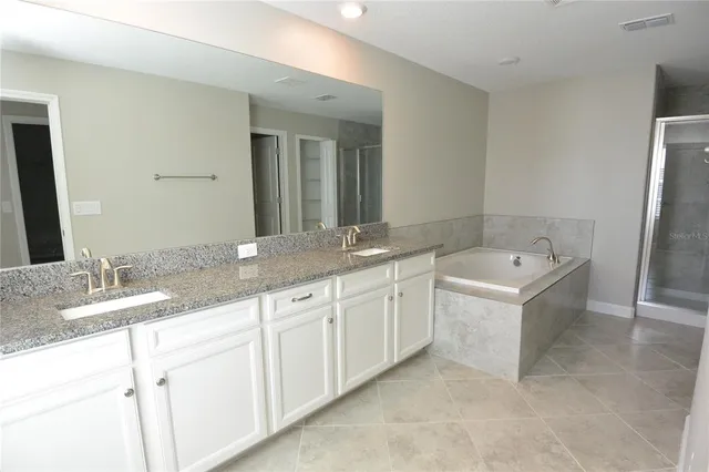 a spacious bathroom with a granite countertop sink mirror and bathtub