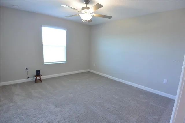 an empty room with a window and a fan