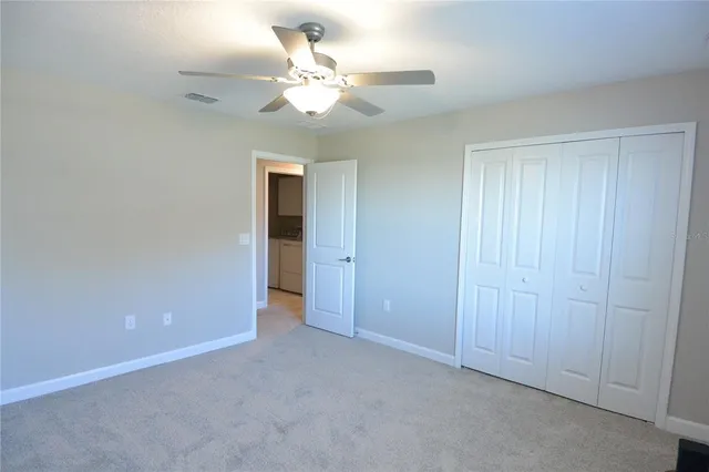 an empty room with a chandelier fan and a bathroom