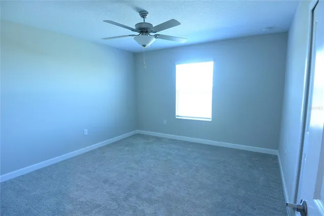 an empty room with a window and a fan