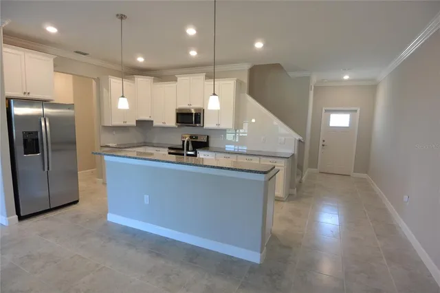 a kitchen with stainless steel appliances granite countertop a refrigerator a sink a stove and a oven