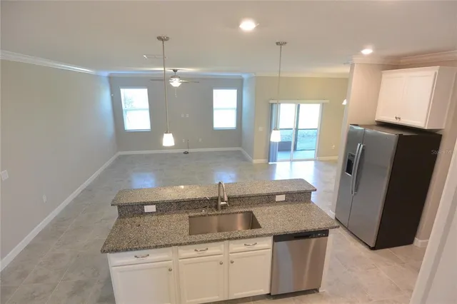 a kitchen with granite countertop a sink and refrigerator