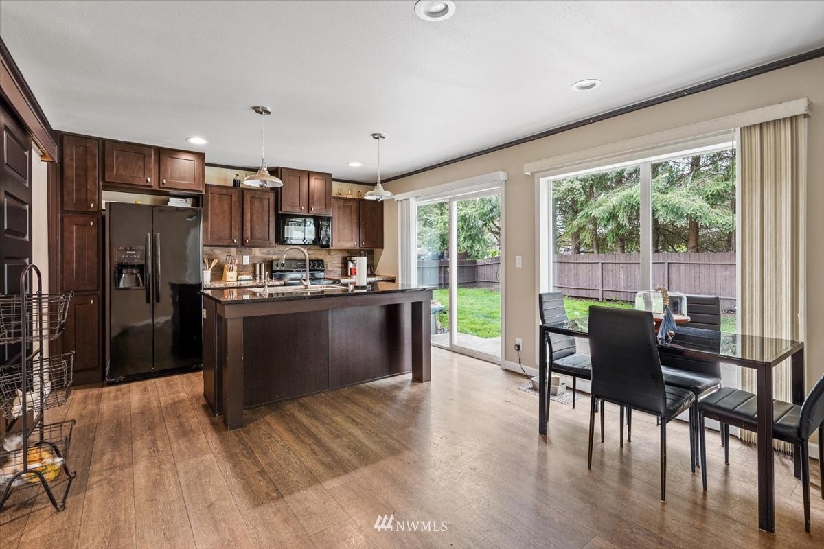 503 Maple Street Pe Ell, WA 98572 - Photo 13 of 27 a kitchen with stainless steel appliances granite countertop a stove top oven a sink dishwasher a dining table and chairs with wooden floor