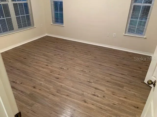 an empty room with wooden floor and windows
