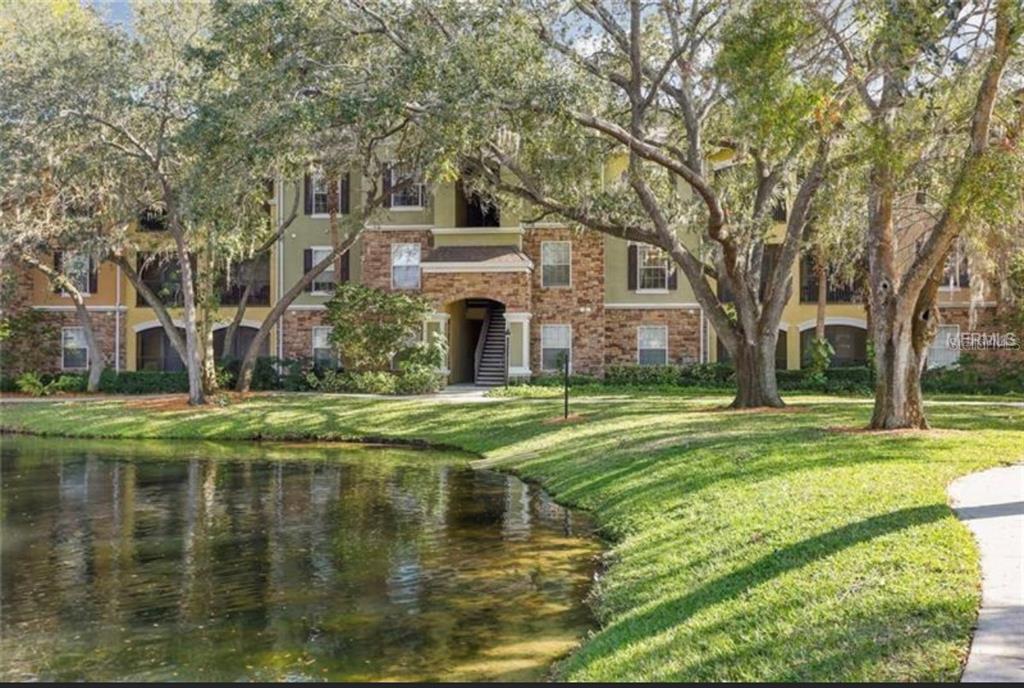 10112 Courtney Palms Boulevard, Unit 201 Tampa, FL 33619 - Photo 5 of 15 a view of a house with a yard and large trees