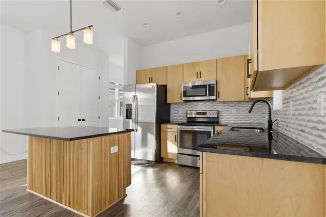 a kitchen with stainless steel appliances granite countertop a refrigerator a stove a sink and a microwave