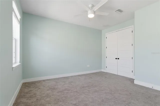 an empty room with a ceiling fan and a window