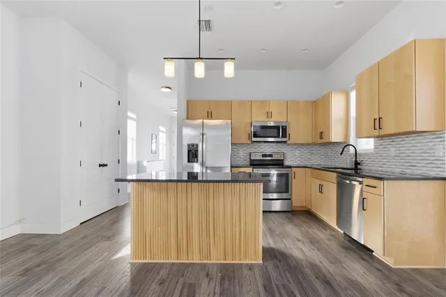 a kitchen with stainless steel appliances a refrigerator a sink dishwasher a stove and white cabinets with wooden floor