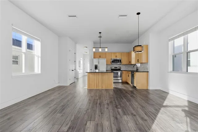 a living room with stainless steel appliances kitchen island granite countertop wooden floors and view of living room