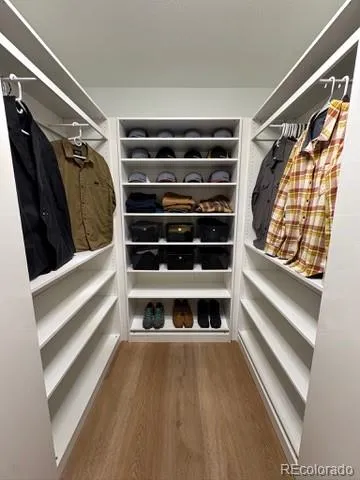 a view of walk in closet with wooden floor and stairs