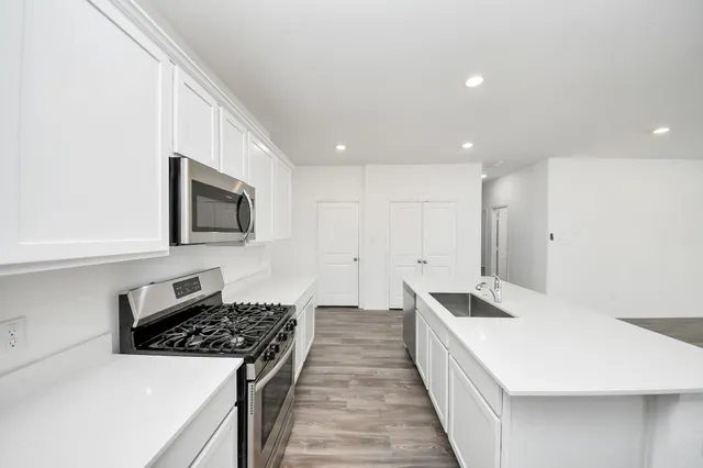 a large white kitchen with wooden floor and a sink