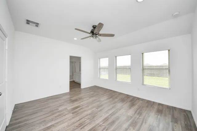 an empty room with wooden floor and windows