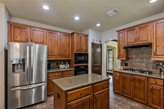 a kitchen with granite countertop stainless steel appliances a refrigerator and a stove top oven