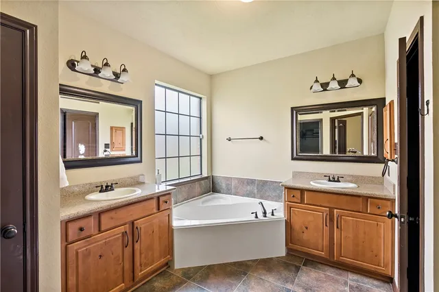 a bathroom with a tub sink double vanity and mirror