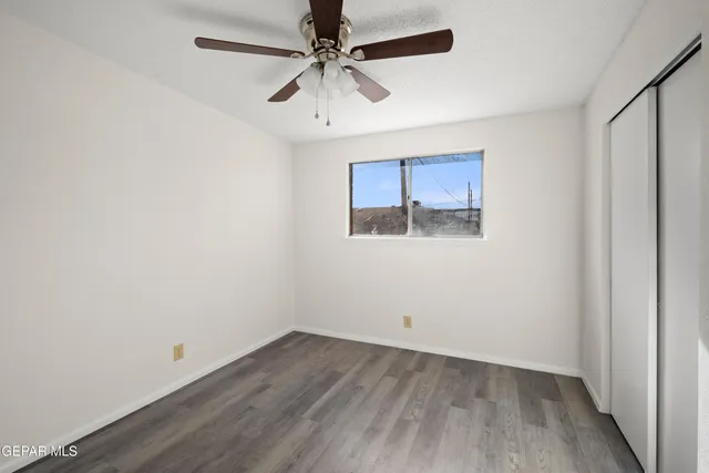 an empty room with a ceiling fan and wooden floor
