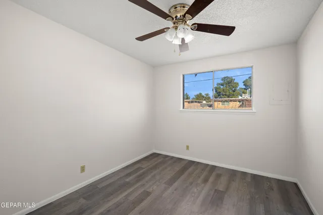 an empty room with wooden floor and ceiling fan