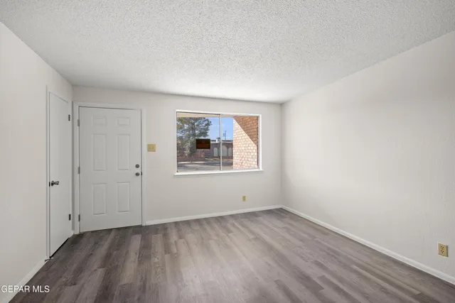 a view of an empty room with wooden floor and a window