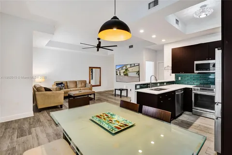 a kitchen with a stove a sink dishwasher a dining table and chairs with wooden floor