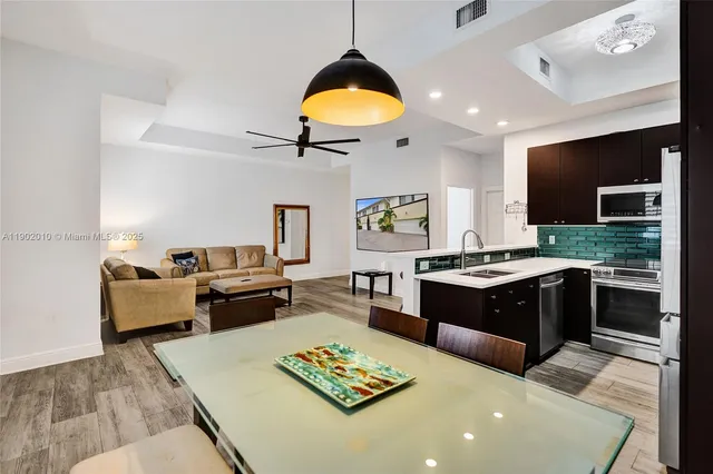 a kitchen with a stove a sink dishwasher a dining table and chairs with wooden floor