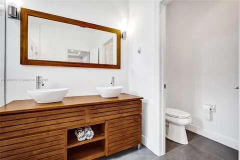 a view of a hallway with wooden floor and a bathroom