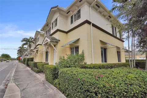 a view of a white house with a yard and palm trees