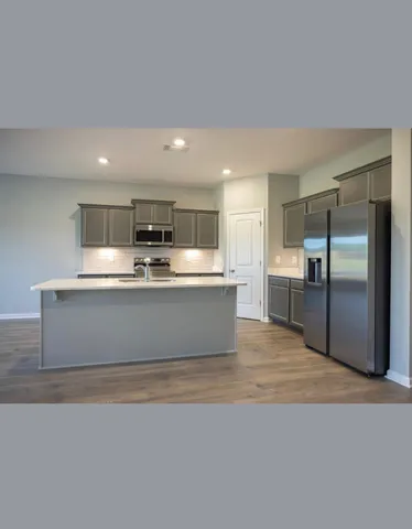 a large kitchen with kitchen island a large counter top stainless steel appliances and cabinets