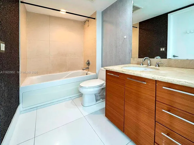 a bathroom with a granite countertop sink toilet mirror and bathtub