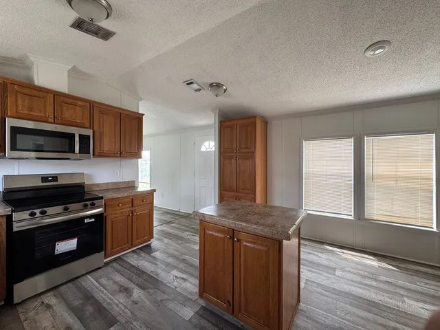 a kitchen with stainless steel appliances granite countertop a stove a sink and a microwave