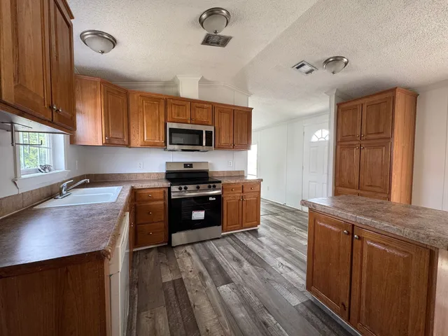 a kitchen with kitchen island granite countertop a sink cabinets and stainless steel appliances