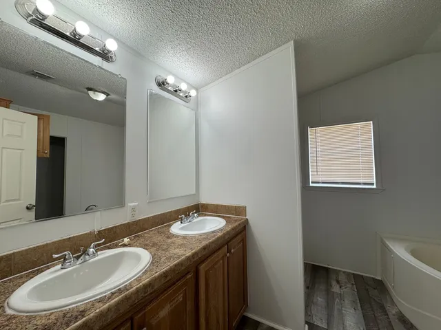 a bathroom with a granite countertop sink a mirror and a bathtub
