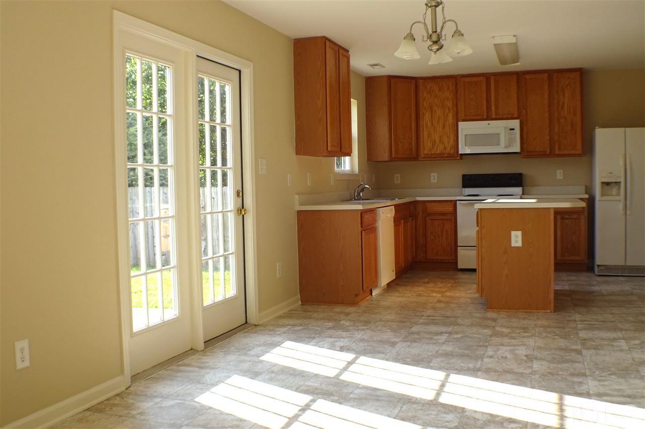 3813 Tyler Bluff Lane Raleigh, NC 27616 - Photo 7 of 25 a kitchen with kitchen island granite countertop wooden cabinets a refrigerator a sink a stove and a window