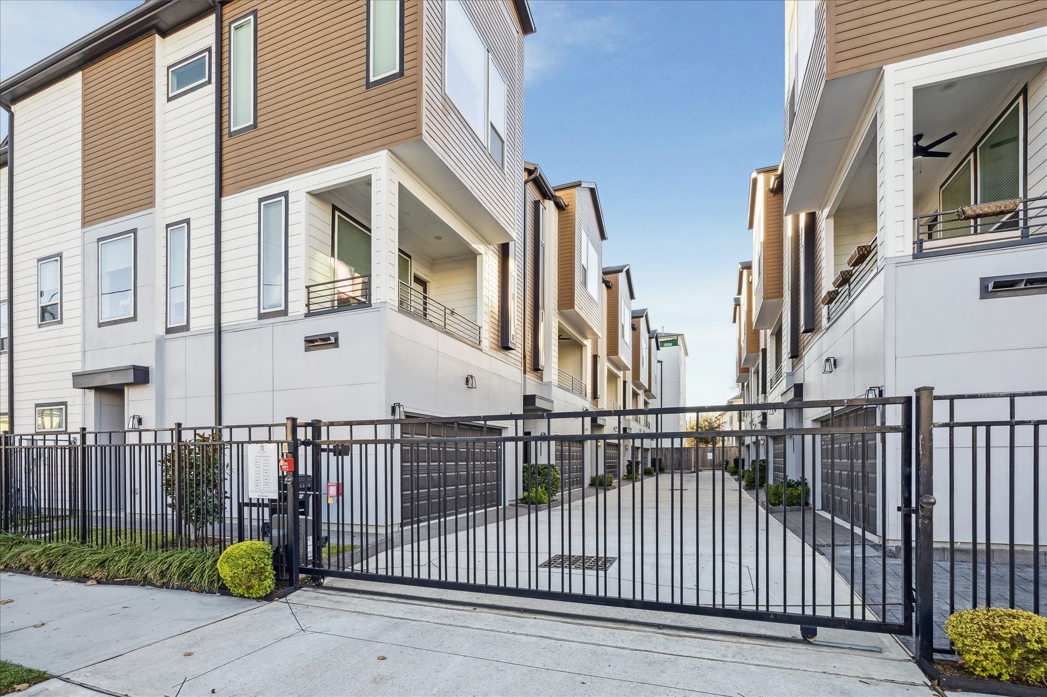 1603 Patterson Street, Unit E Houston, TX 77007 - Photo 3 of 32 Modern townhouse complex with a gated entrance, featuring clean lines and contemporary architecture. The units have balconies and large windows, offering a secure, stylish living environment.