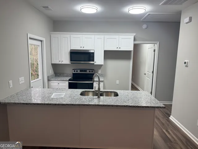 a kitchen with kitchen island granite countertop a sink a microwave a refrigerator and cabinets