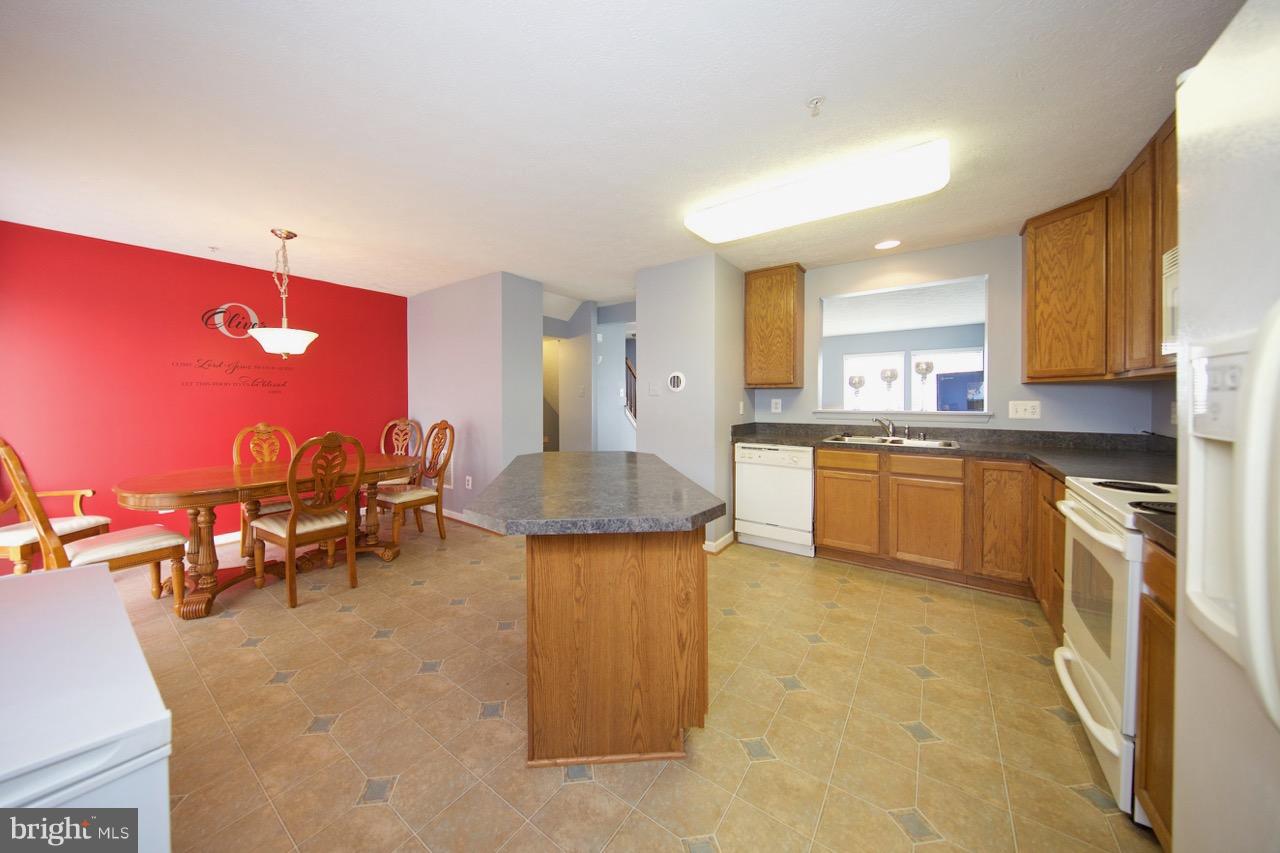 9701 Selfridge Road Baltimore, MD 21220 - Photo 8 of 29 a kitchen with stainless steel appliances granite countertop a sink a stove top oven a dining table and chairs with wooden floor