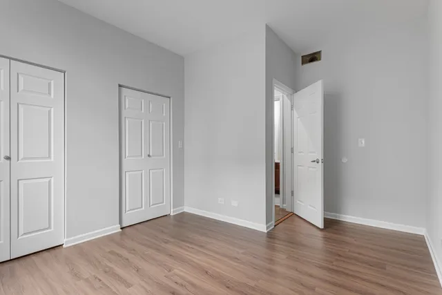 a view of an empty room with wooden floor and closet