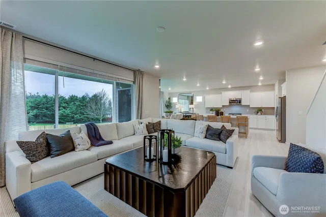 a living room with furniture kitchen view and a large window