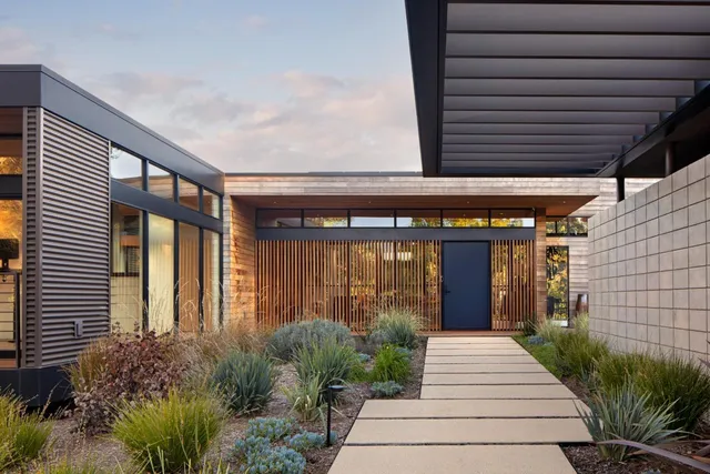 a view of a house with potted plants and a table and chairs