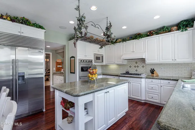 a kitchen with stainless steel appliances granite countertop a sink a stove and refrigerator