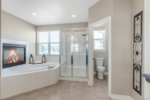 a spacious bathroom with a tub mirror and toilet