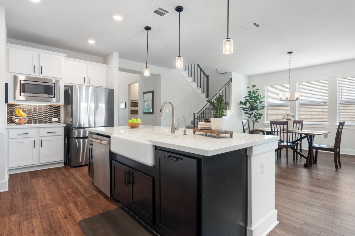 Welcome to 456 Running Bird in Parten Ranch. The gourmet kitchen features an upgraded porcelain farmhouse sink and sleek black and white cabinets.