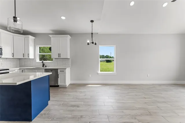 a large kitchen with a sink a window and stainless steel appliances