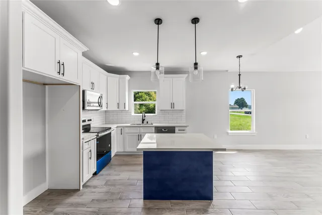 a kitchen with kitchen island granite countertop a sink a counter top space appliances and cabinets