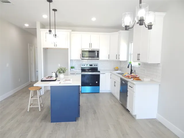 a kitchen with stainless steel appliances a stove top oven a sink dishwasher and a refrigerator