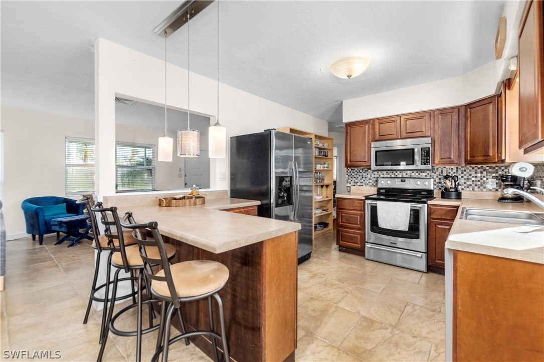 1448 Byron Road Fort Myers, FL 33919 - Photo 13 of 30 a kitchen with stainless steel appliances a table chairs refrigerator and a stove top oven