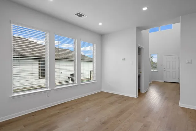 an empty room with wooden floor and windows