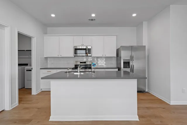 a large kitchen with stainless steel appliances granite countertop a refrigerator a stove a sink and a microwave