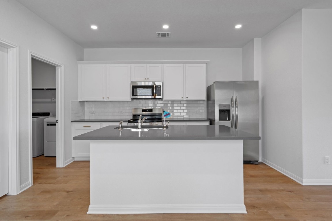 145 Hatari Trail Jarrell, TX 76537 - Photo 6 of 37 a large kitchen with stainless steel appliances granite countertop a refrigerator a stove a sink and a microwave