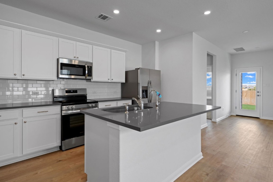 145 Hatari Trail Jarrell, TX 76537 - Photo 8 of 37 a kitchen with stainless steel appliances granite countertop a sink a stove and a refrigerator
