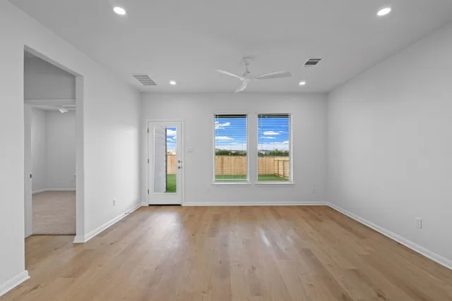 an empty room with wooden floor and windows