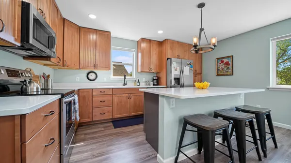 a kitchen with stainless steel appliances a dining table chairs sink refrigerator and microwave